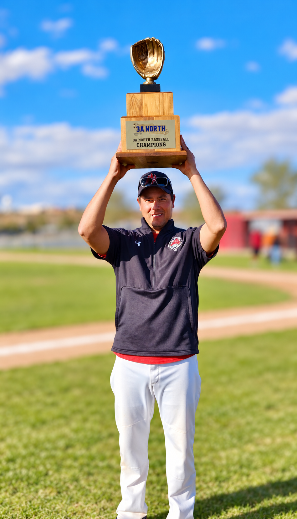Coach Martinez holding a baseball championship trophy above his head
